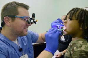 a dental resident checks a student’s teeth