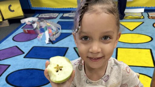 A child shows the start shape inside of an apple.