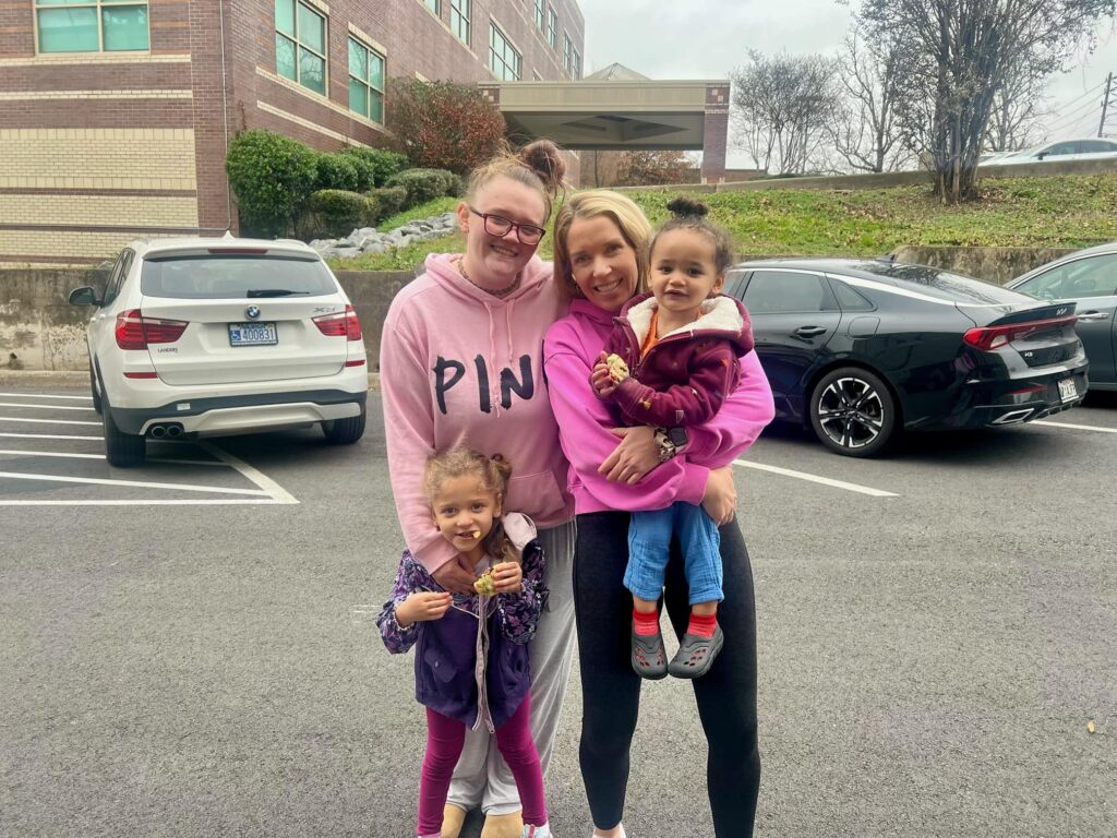 A woman and her 2 children pose for a photo with another woman who sponsored her family for the holidays.