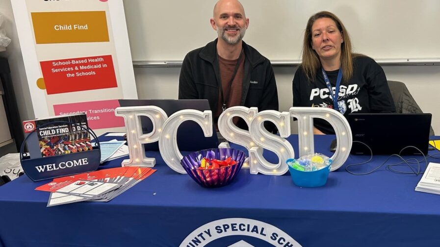 A man and woman from Pulaski County Special School District are sitting at a table waiting to help families with enrollment.