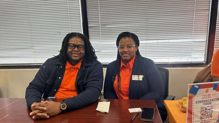 A man and woman are sitting at a table waiting to help families with enrollment.