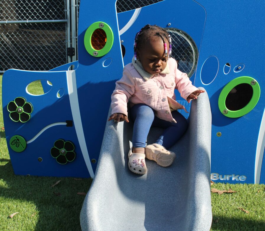Little girl is going down the slide on the new playground equipment.