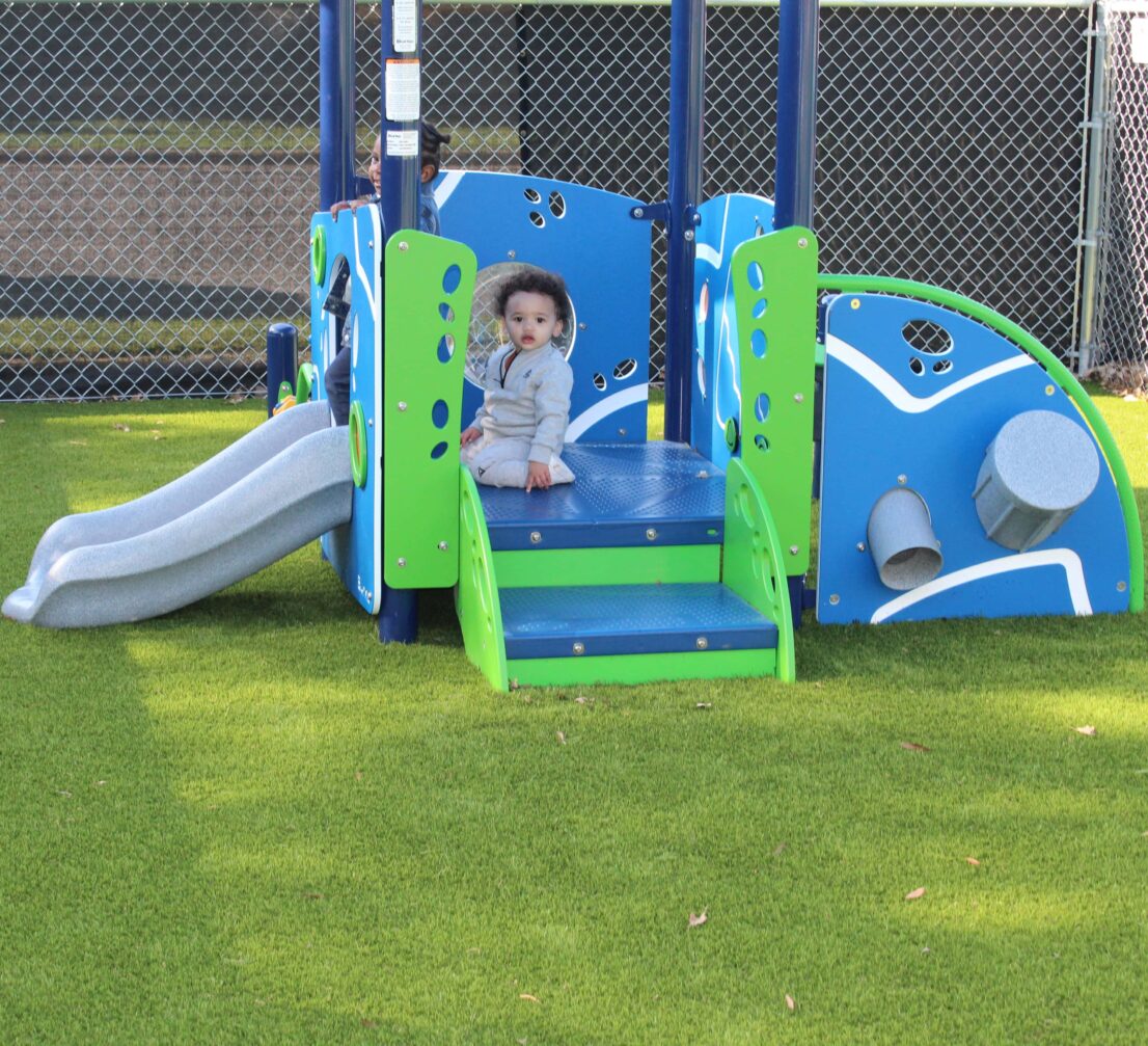 Little boy outside enjoying the new playground equipment. It looks like he is about to go down the slide.