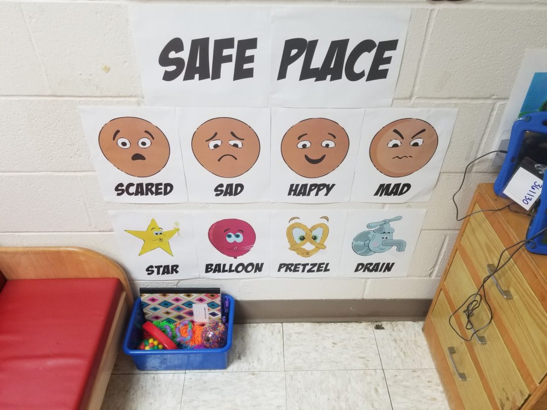 Picture shows a “Safe Place” corner in a classroom with pictures demonstrating different emotions: Scared, Sad, Happy, Mad
