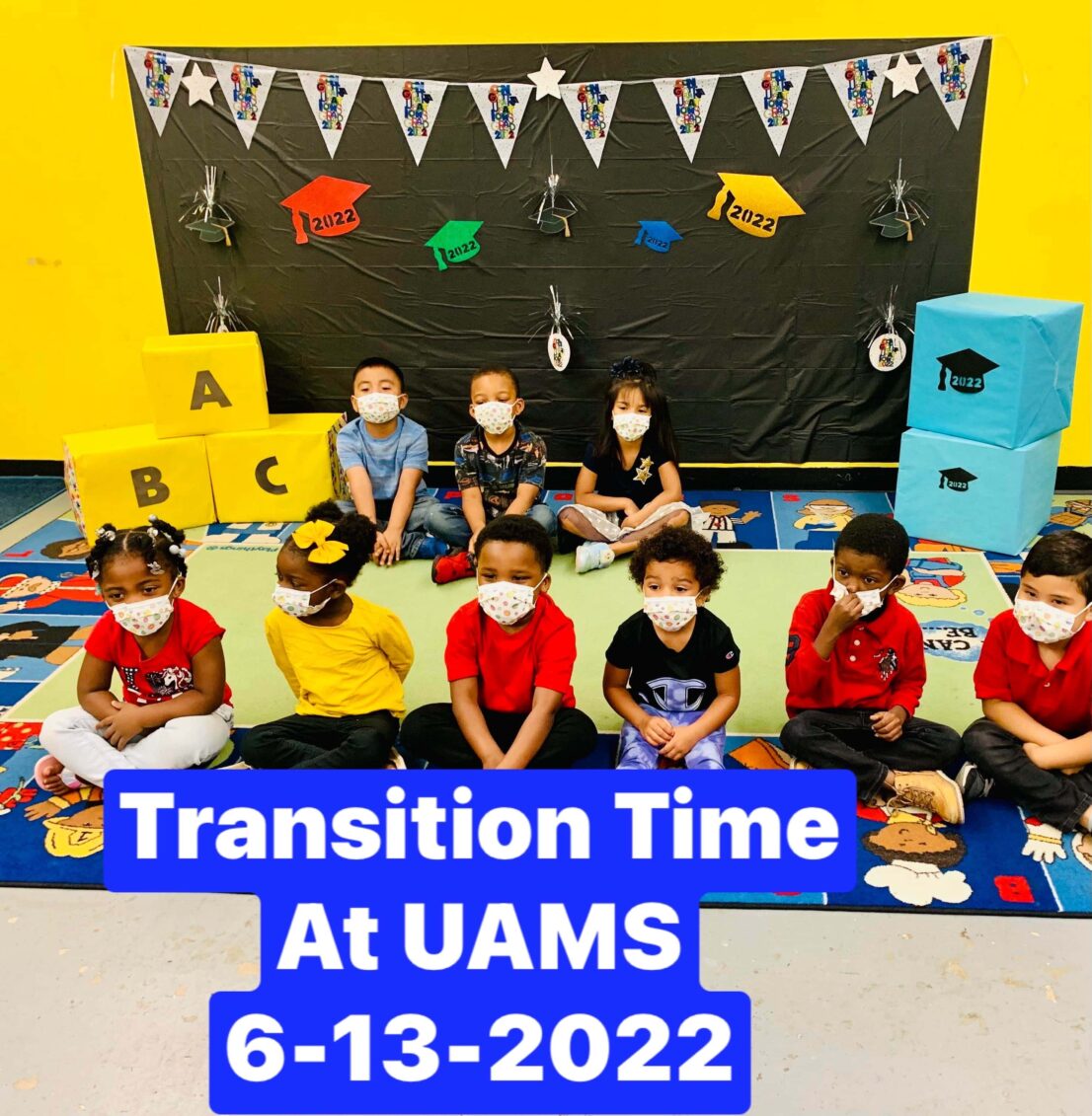 Children sit in two rows on a rug with a decorative background and the caption Transition Time at UAMS 6-13-2022