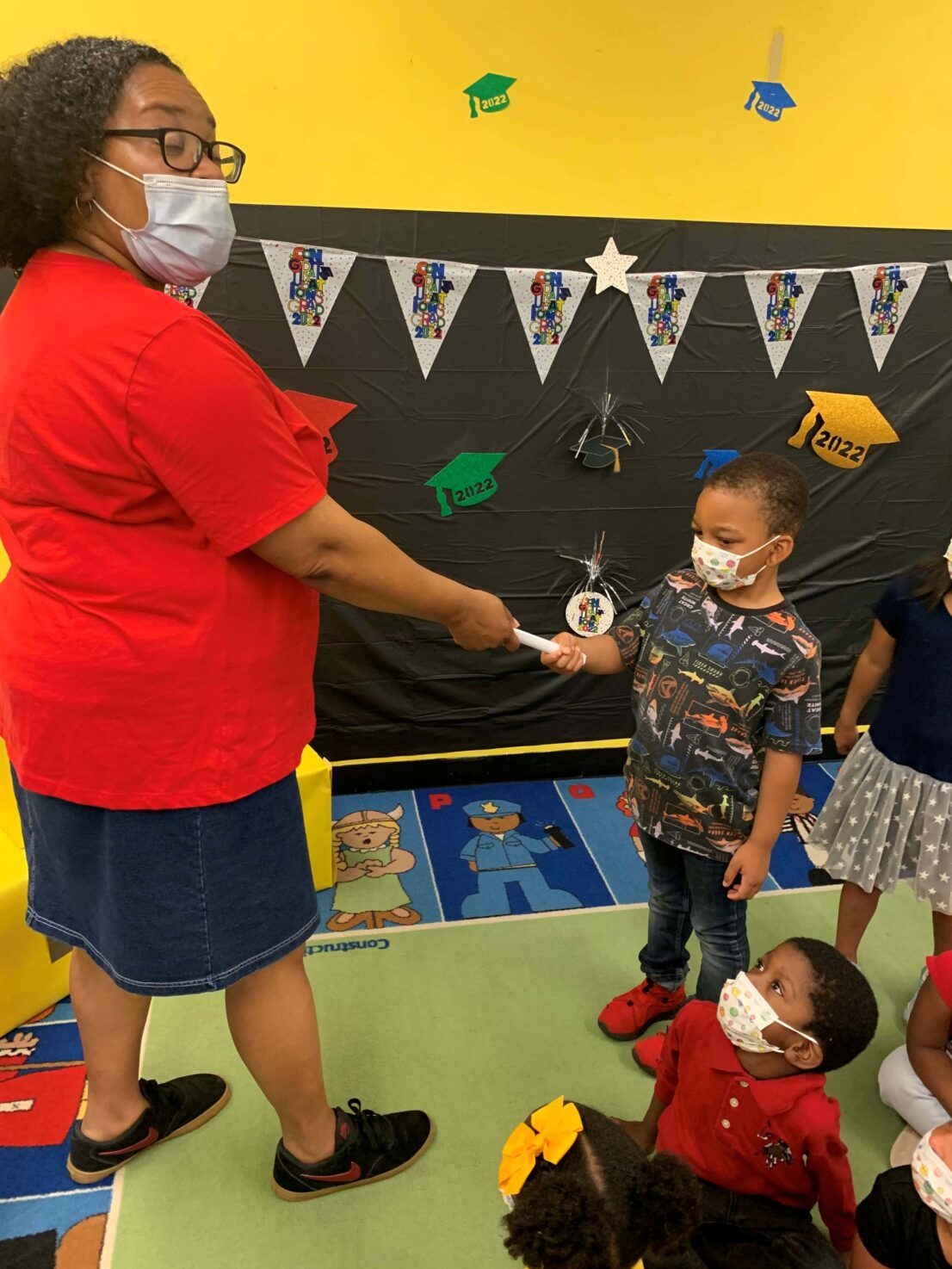 Teacher hands child his certificate for completing the Head Start program.