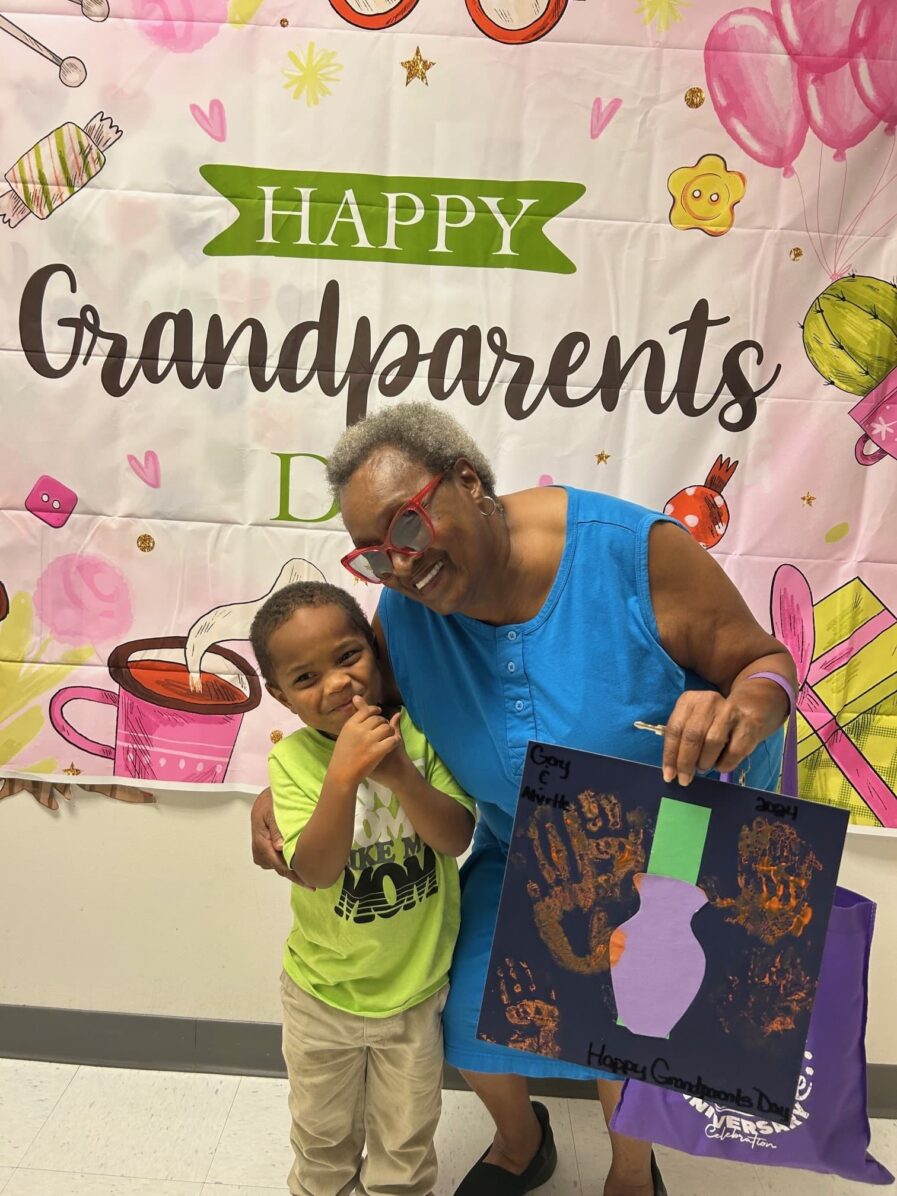 grandmother standing with grandson who is holding a picture they made