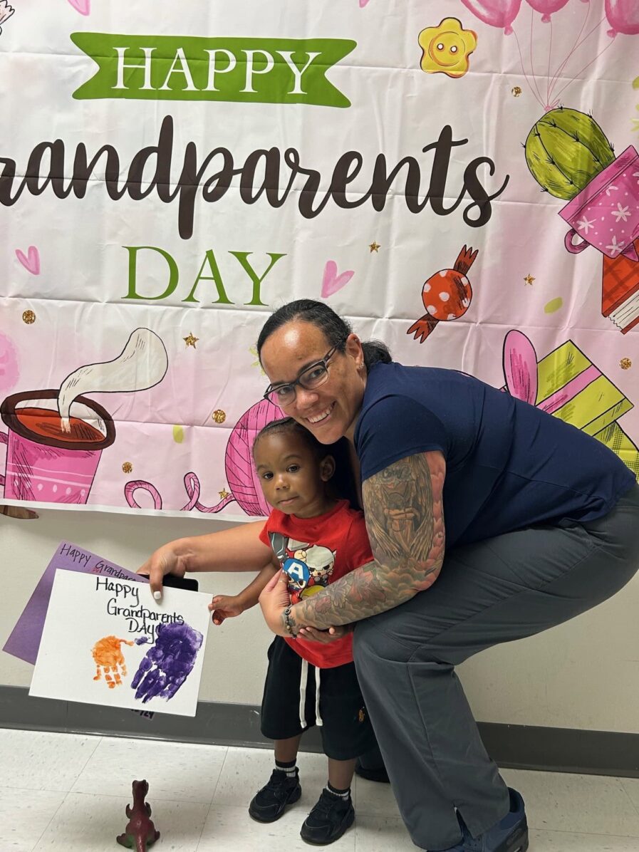 grandmother standing with grandson who is holding a picture they made