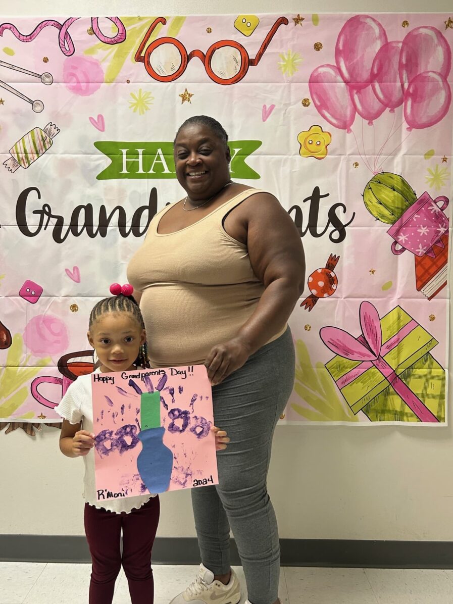 grandmother standing with granddaughter who is holding a picture they made