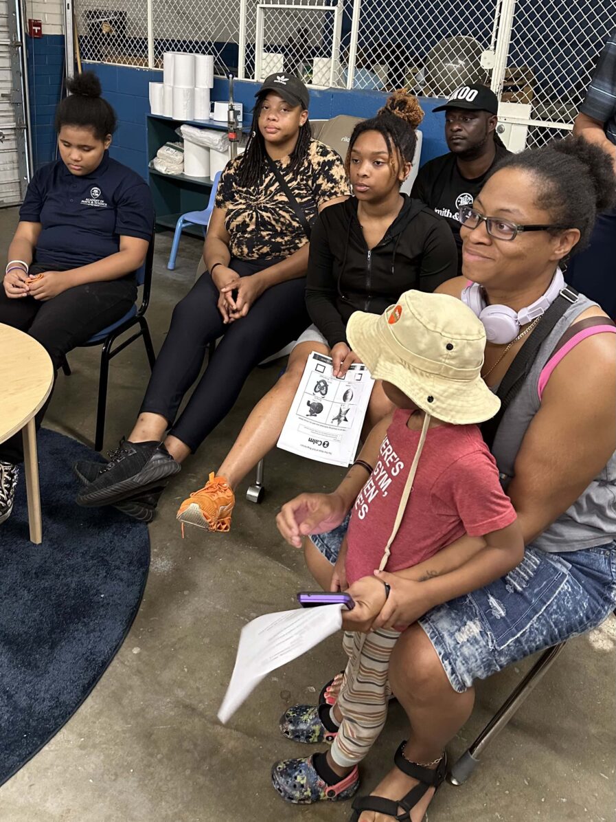 parents sitting, one child is standing between a parent's legs