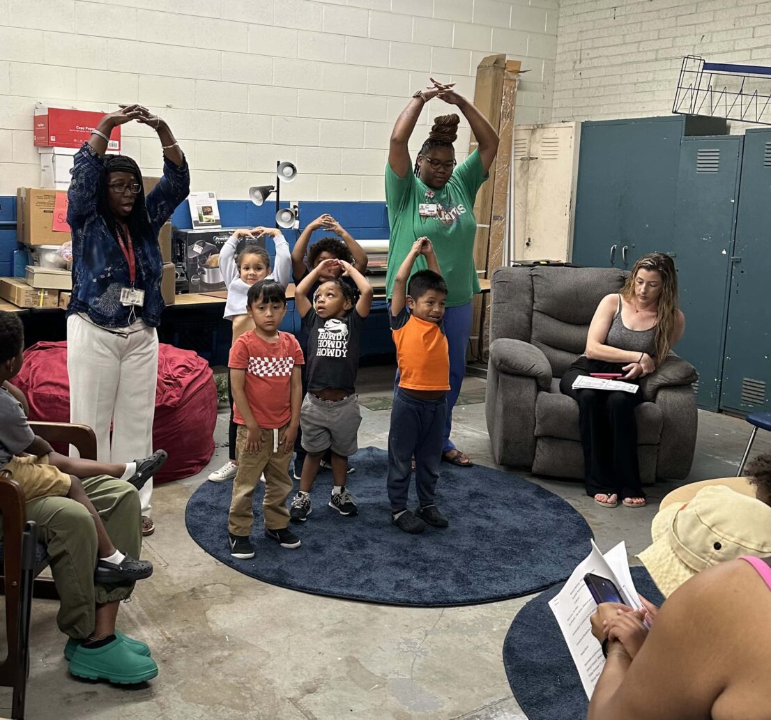 teachers and students standing with their arm above their heads