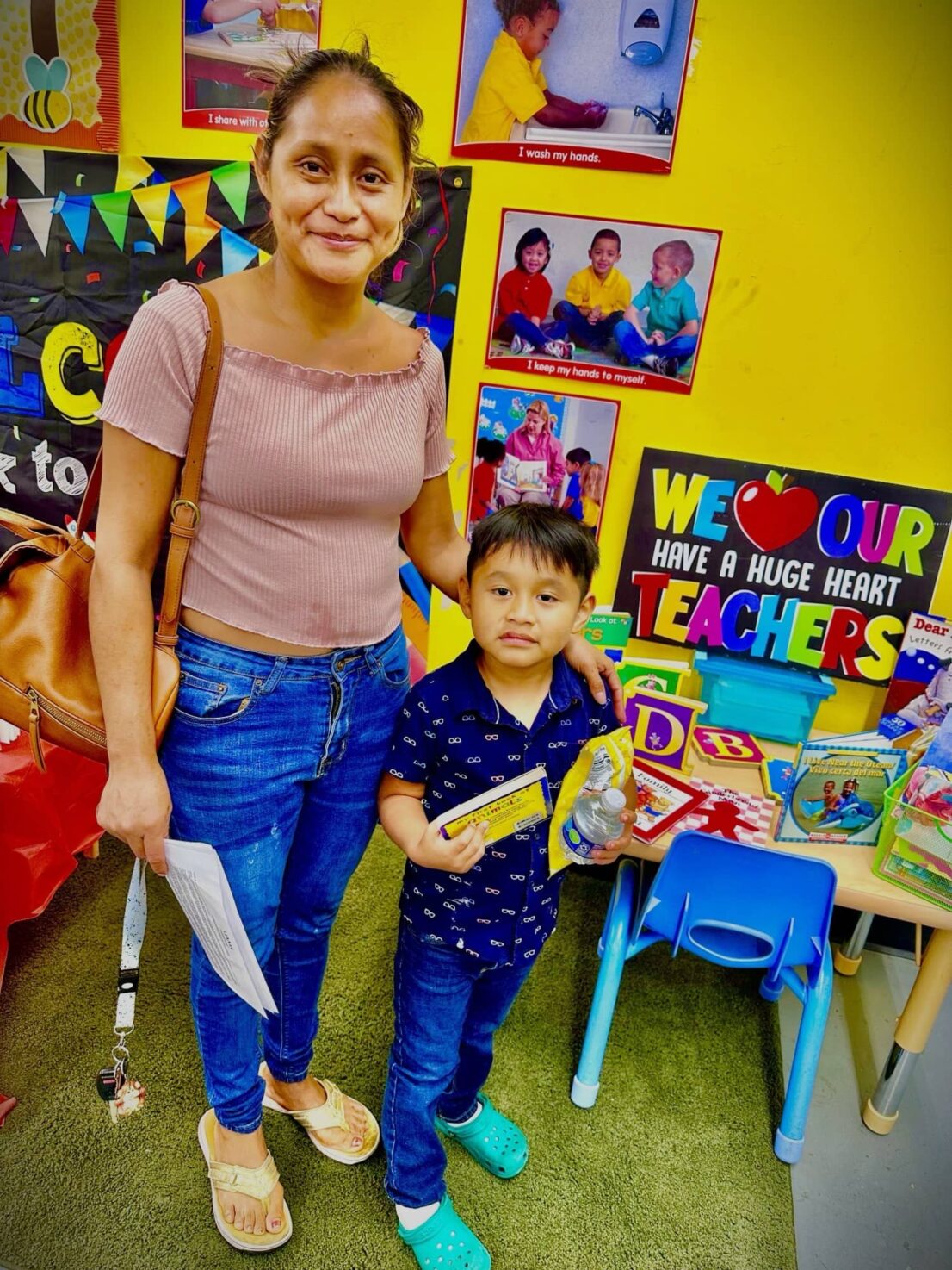 mother and child posing for a photo, the child is holding a book