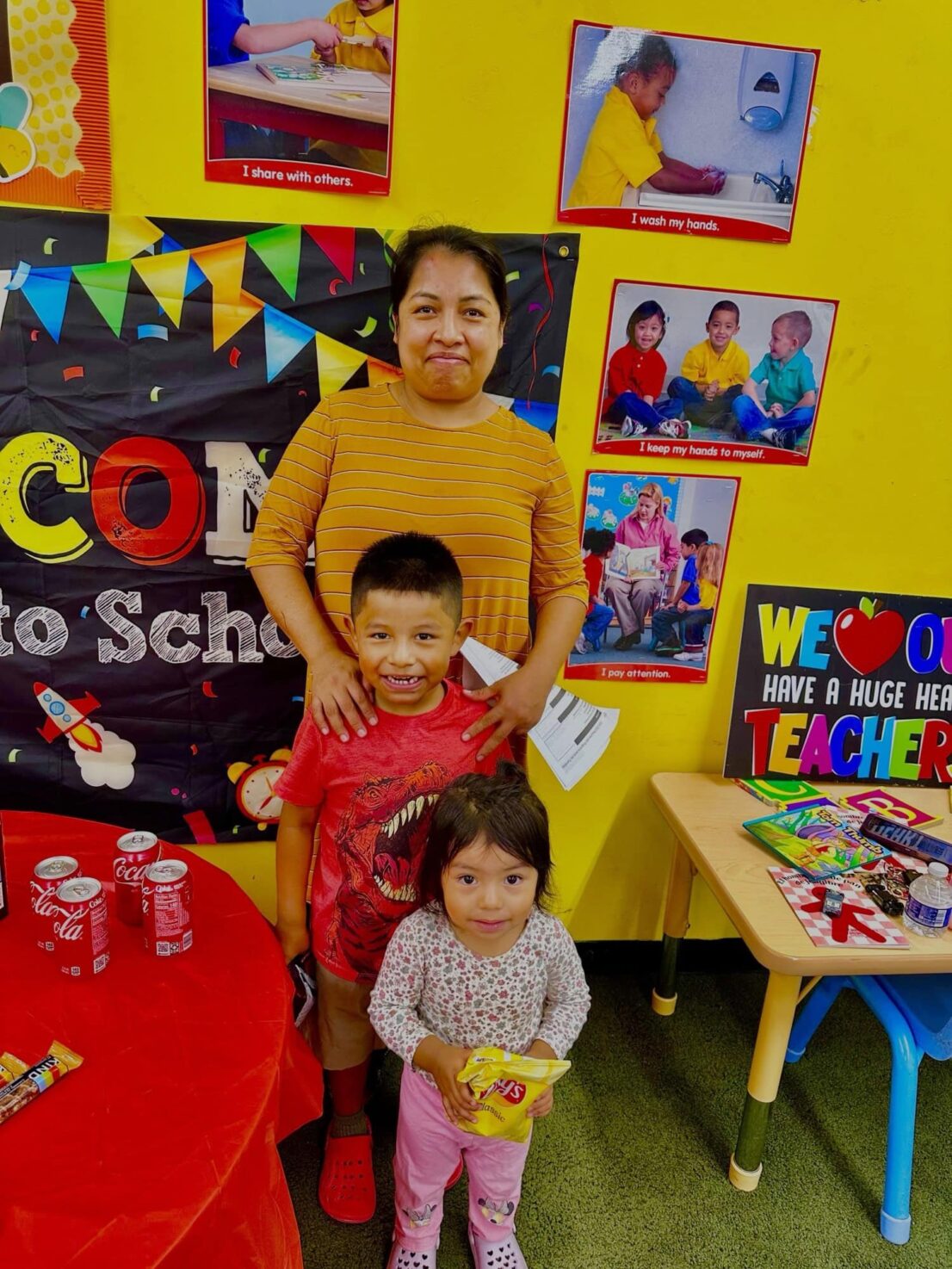 A mother poses for a photo with her son in front of her and her daughter, who is younger in front of the son