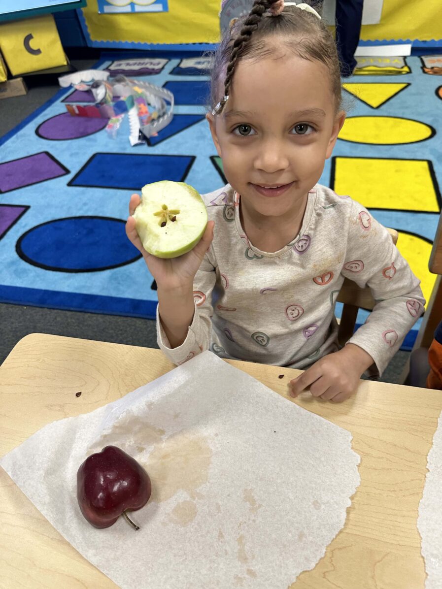 A child shows the start shape inside of an apple.