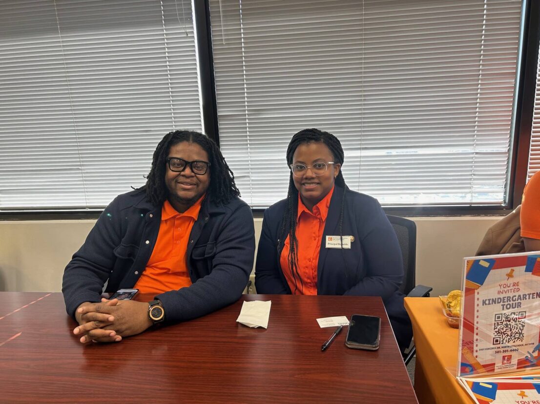 A man and woman are sitting at a table waiting to help families with enrollment.